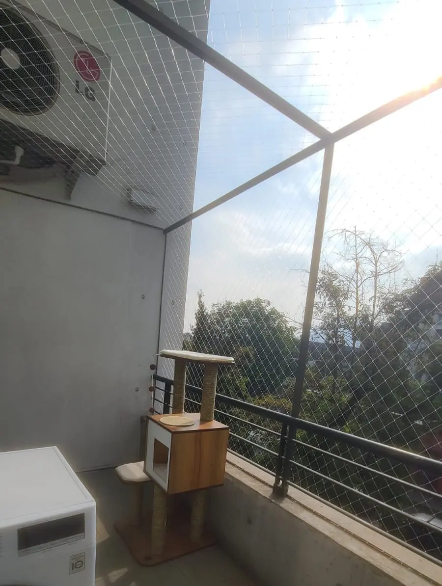 Malla de seguridad para gatos instalada en el balcón de un departamento en Santiago, con un rascador junto al ventanal