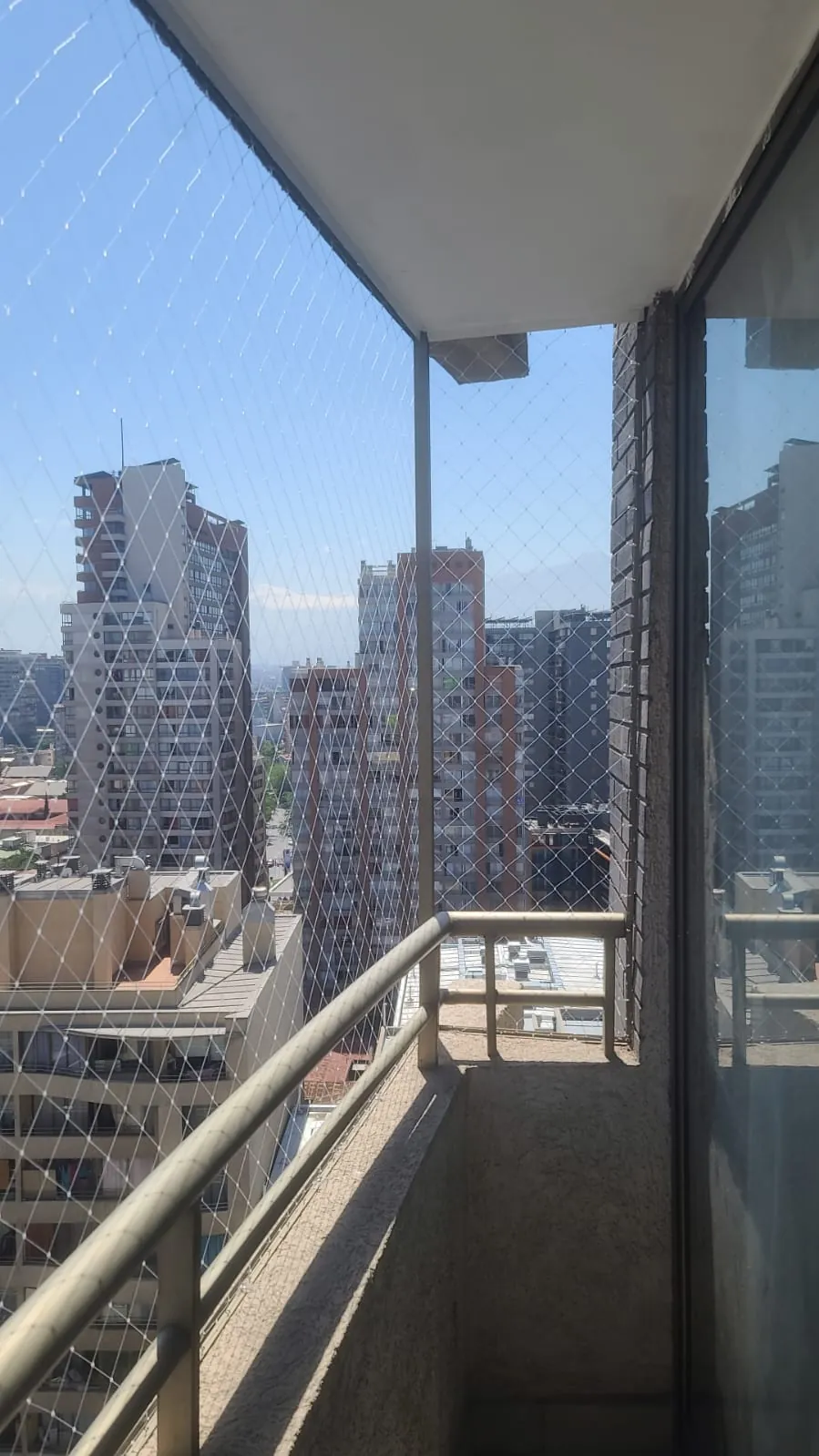 Instalación de malla de seguridad para gatos en el balcón de un departamento en altura, con la malla cerrando el vano de piso a cielo entre edificios de Santiago